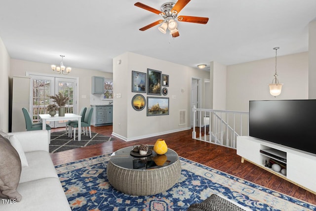 living area featuring ceiling fan with notable chandelier, visible vents, baseboards, and wood finished floors