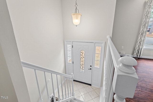 tiled entryway with stairs and baseboards