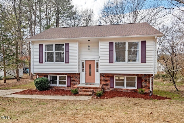 split foyer home with a shingled roof, a front yard, and brick siding