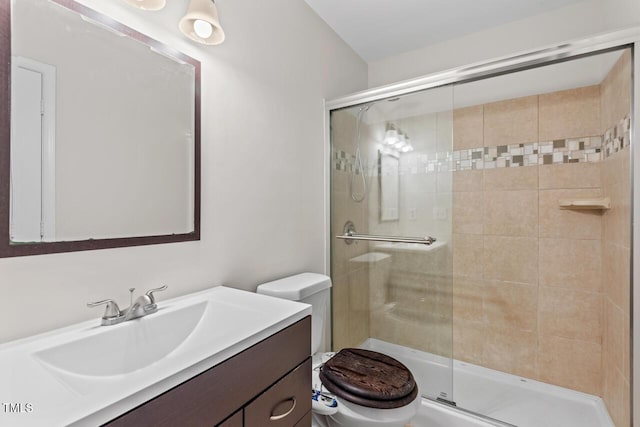 full bathroom featuring a stall shower, vanity, and toilet