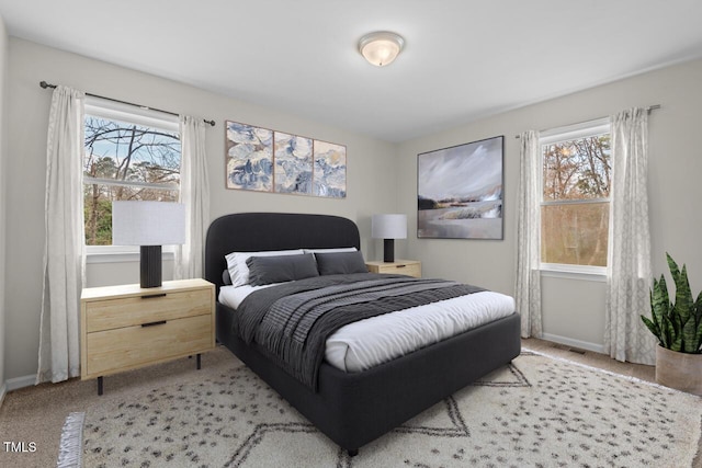 bedroom with light carpet, multiple windows, and baseboards