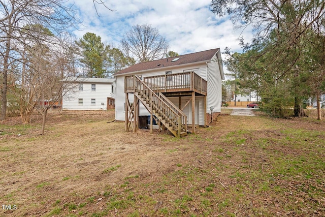 rear view of property featuring stairs, a deck, and a lawn