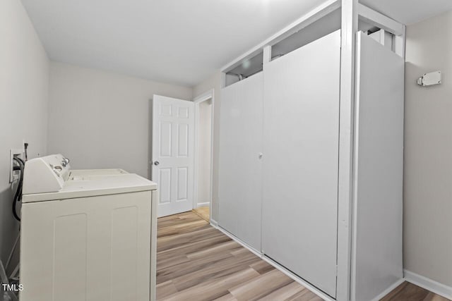 laundry room featuring light wood finished floors, laundry area, separate washer and dryer, and baseboards