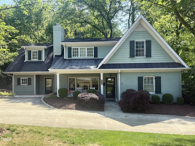 3504 Rock Creek Dr, Raleigh, NC 27609 - view of front of house featuring a standing seam roof, covered porch, a chimney, and brick siding