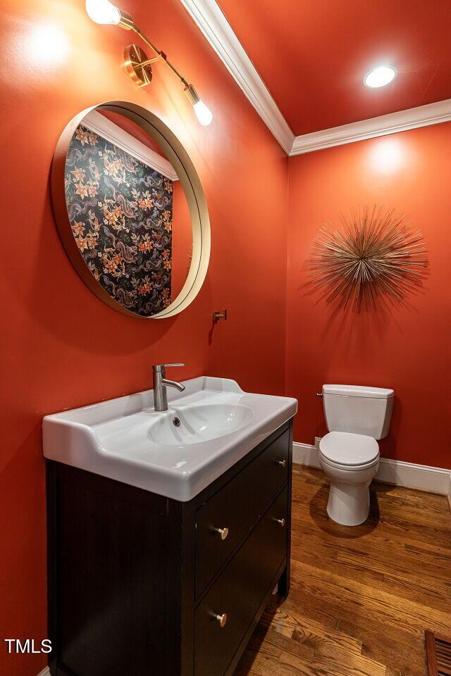 3504 Rock Creek Dr, Raleigh, NC 27609 - half bathroom featuring vanity, ornamental molding, wood finished floors, toilet, and baseboards