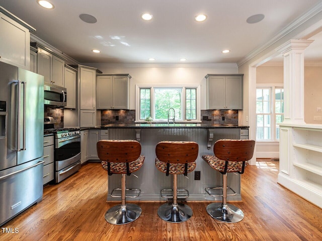 3504 Rock Creek Dr, Raleigh, NC 27609 - kitchen with a kitchen breakfast bar, crown molding, appliances with stainless steel finishes, dark countertops, and gray cabinetry