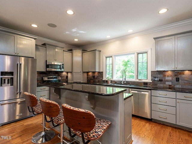 3504 Rock Creek Dr, Raleigh, NC 27609 - kitchen with appliances with stainless steel finishes, a breakfast bar, a sink, gray cabinets, and ornamental molding