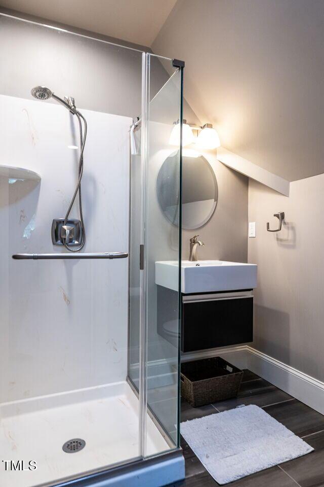 3504 Rock Creek Dr, Raleigh, NC 27609 - full bathroom featuring vanity, baseboards, wood finished floors, and a stall shower