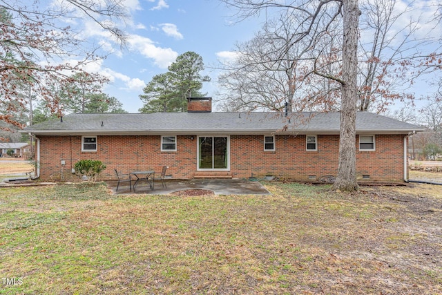 back of property featuring brick siding, crawl space, a patio area, a yard, and a chimney