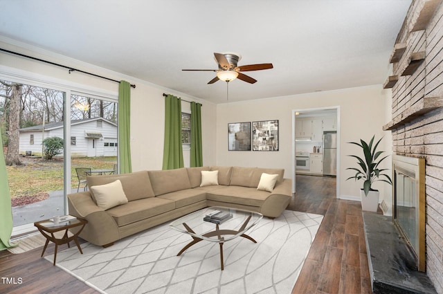 living area with a ceiling fan, ornamental molding, wood finished floors, and a fireplace