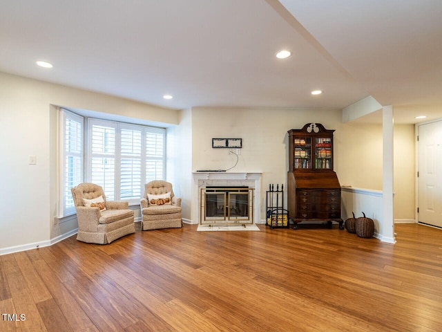 unfurnished room featuring a fireplace with flush hearth, baseboards, wood finished floors, and recessed lighting