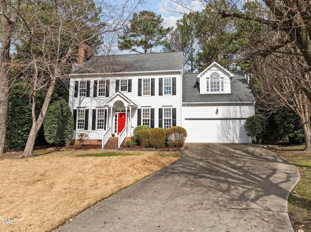 colonial house with roof with shingles, a front yard, crawl space, a garage, and driveway