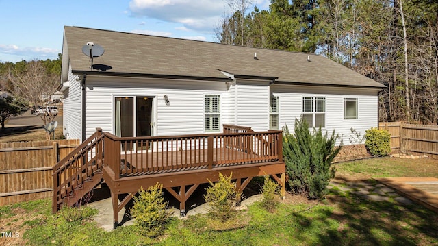 back of property with roof with shingles, fence, and a deck