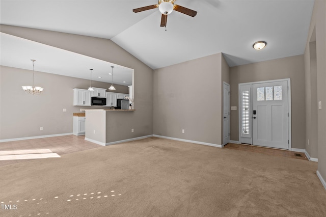 unfurnished living room featuring lofted ceiling, light colored carpet, baseboards, and ceiling fan with notable chandelier