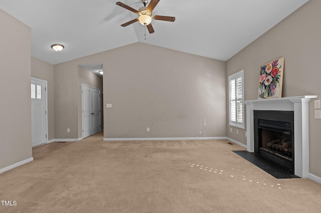 unfurnished living room with lofted ceiling, light colored carpet, a fireplace with flush hearth, a ceiling fan, and baseboards