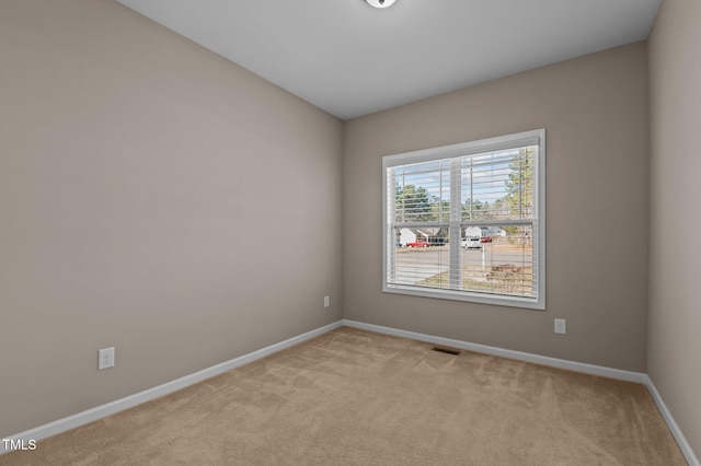 unfurnished room with baseboards, visible vents, and light colored carpet