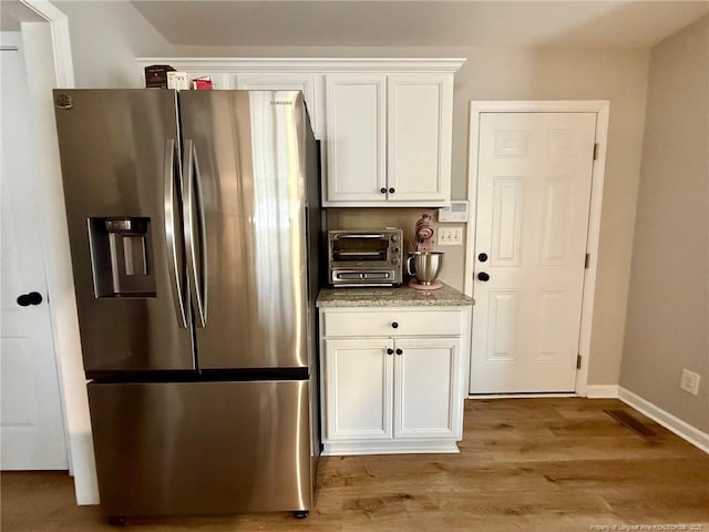 kitchen with white cabinets, stainless steel fridge, and light hardwood / wood-style floors