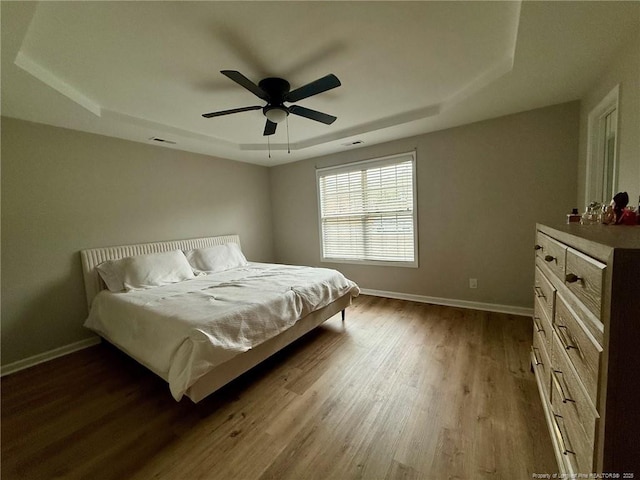 bedroom featuring a raised ceiling, hardwood / wood-style flooring, and ceiling fan