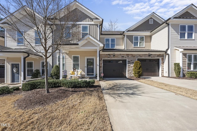 townhome / multi-family property with a garage, stone siding, board and batten siding, and concrete driveway