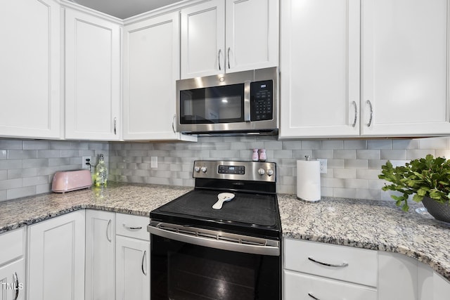 kitchen with stainless steel appliances, white cabinets, decorative backsplash, and light stone countertops