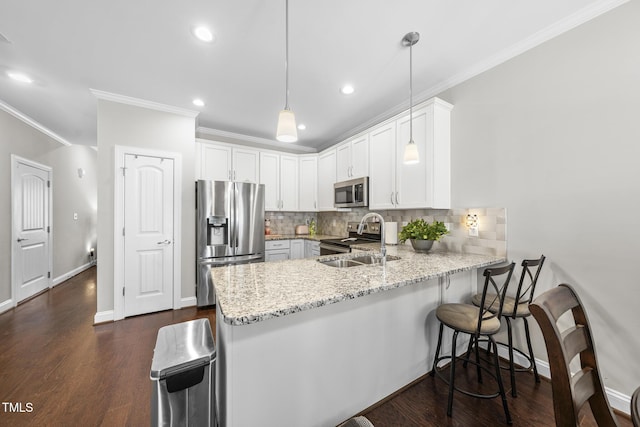 kitchen featuring backsplash, appliances with stainless steel finishes, a sink, light stone countertops, and a peninsula