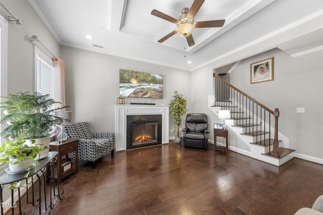 living area featuring a tray ceiling, stairs, visible vents, and wood finished floors