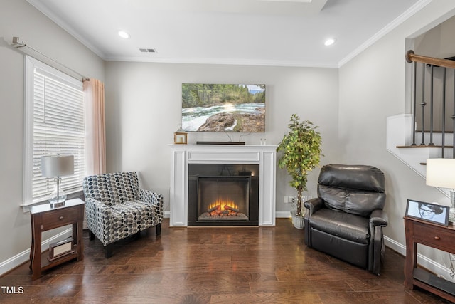 sitting room with ornamental molding, wood finished floors, visible vents, and baseboards