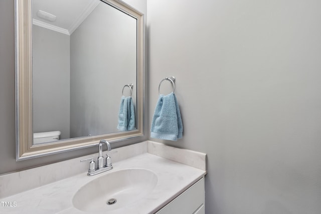 bathroom with toilet, ornamental molding, and vanity