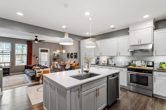 kitchen with appliances with stainless steel finishes, pendant lighting, sink, white cabinetry, and a kitchen island with sink