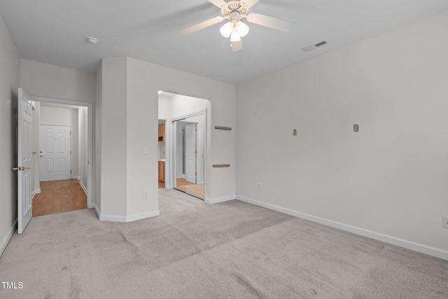 unfurnished bedroom featuring light carpet, ensuite bath, a closet, and ceiling fan
