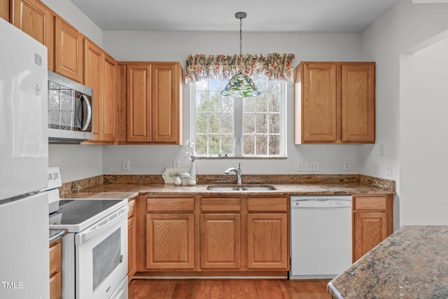 kitchen featuring decorative light fixtures, sink, white appliances, light stone counters, and light wood-type flooring