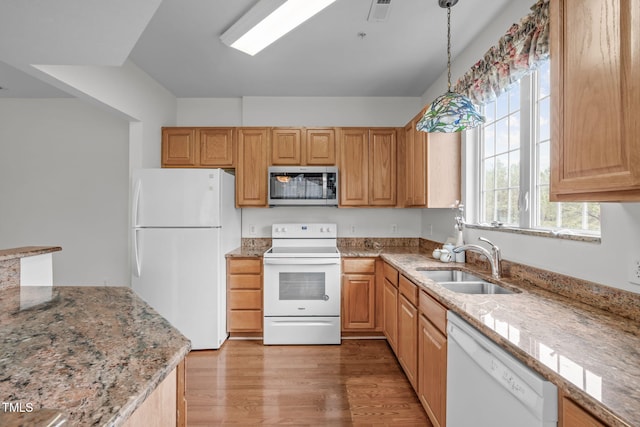kitchen featuring pendant lighting, sink, white appliances, light stone counters, and light hardwood / wood-style floors