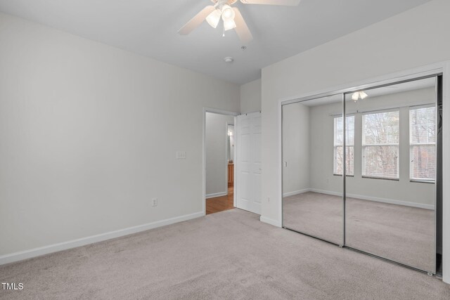 unfurnished bedroom featuring ceiling fan, light colored carpet, and a closet