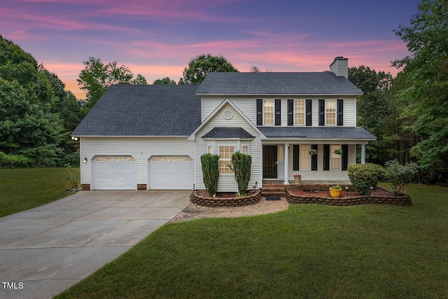 view of front of home with a garage, a chimney, a yard, and driveway