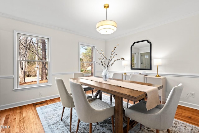 dining area with crown molding, baseboards, and wood finished floors