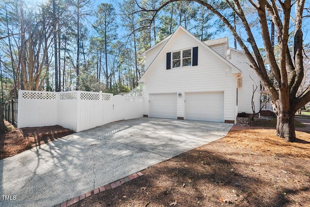 view of side of property featuring fence, an attached garage, and driveway