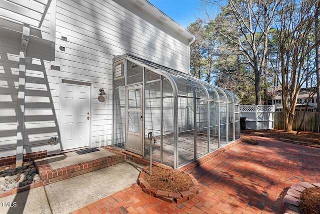 view of exterior entry with a patio and fence