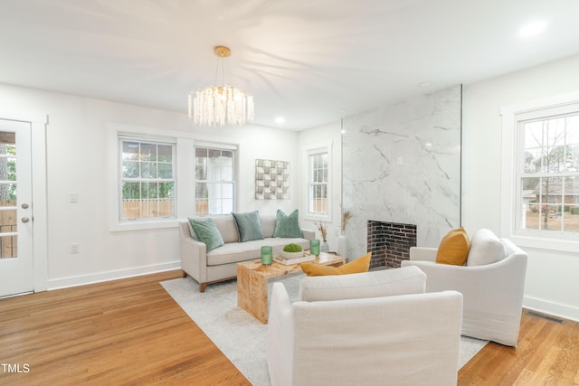 living room featuring a premium fireplace, a notable chandelier, and light wood-type flooring