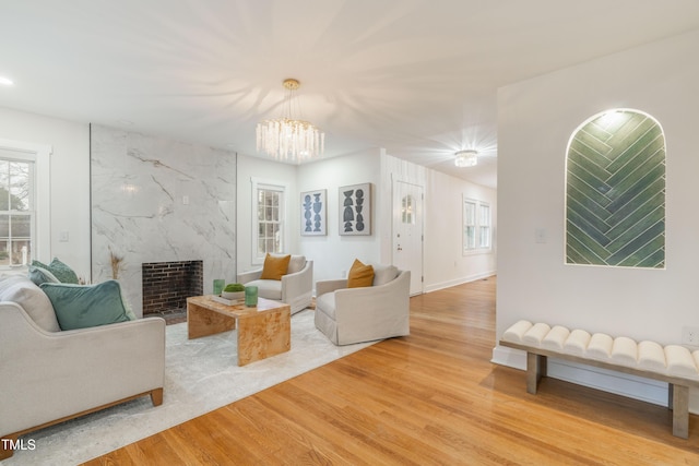 living room featuring a high end fireplace, light hardwood / wood-style floors, and a chandelier