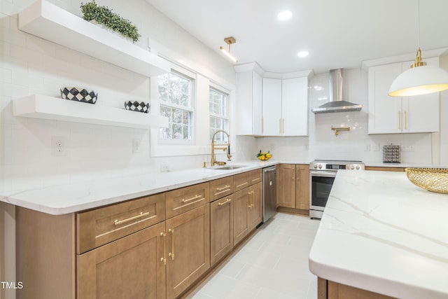 kitchen with wall chimney exhaust hood, sink, white cabinetry, stainless steel appliances, and light stone countertops