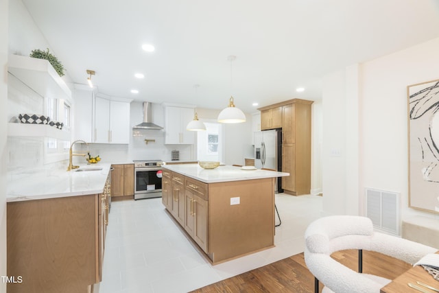 kitchen featuring a kitchen island, appliances with stainless steel finishes, sink, white cabinets, and wall chimney range hood