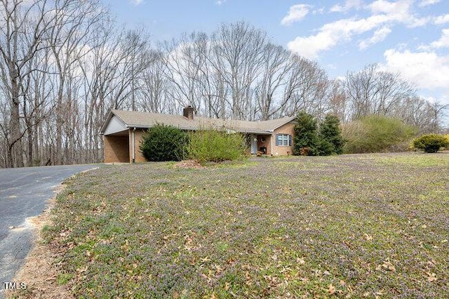 view of side of property featuring a yard, driveway, and a chimney