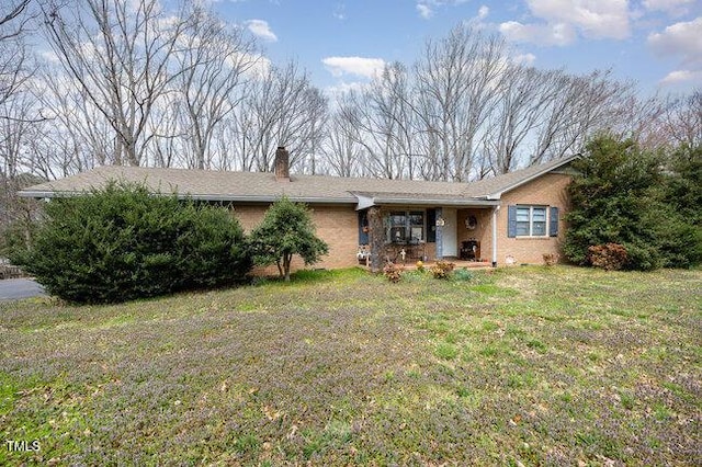 ranch-style home with brick siding, a chimney, and a front lawn