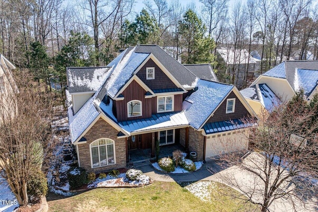 craftsman house with concrete driveway, board and batten siding, metal roof, stone siding, and a front lawn