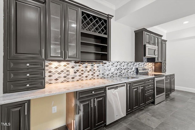 kitchen with crown molding, stainless steel appliances, backsplash, glass insert cabinets, and light stone countertops