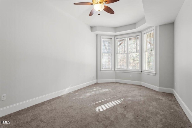 carpeted empty room featuring a ceiling fan and baseboards