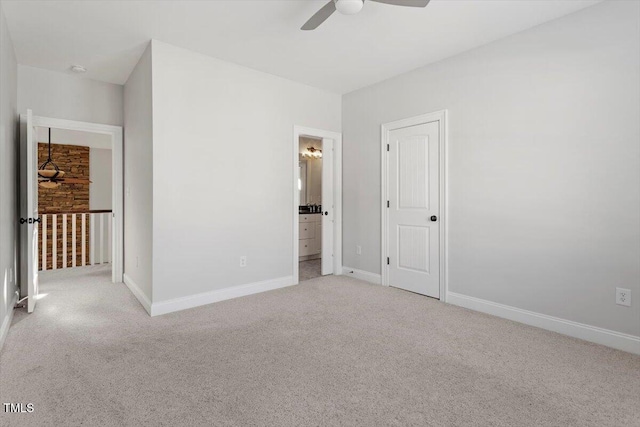 unfurnished bedroom featuring light colored carpet, ceiling fan, ensuite bath, and baseboards