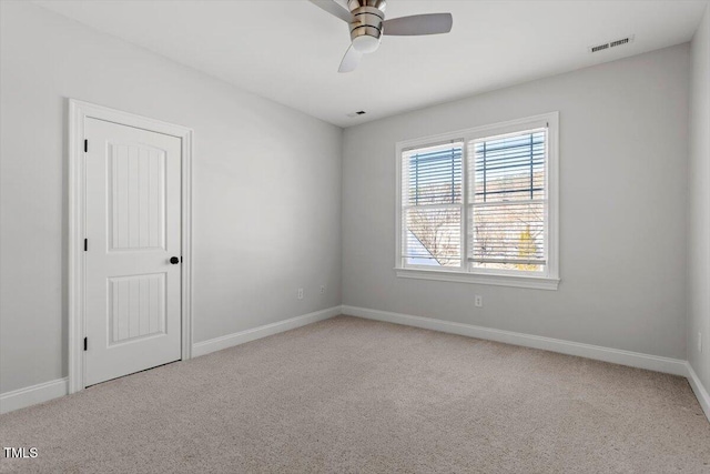 spare room with baseboards, visible vents, a ceiling fan, and light colored carpet