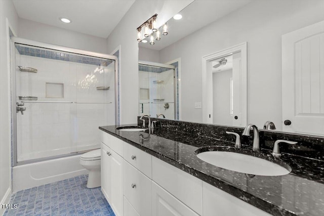 bathroom with double vanity, a sink, toilet, and bath / shower combo with glass door