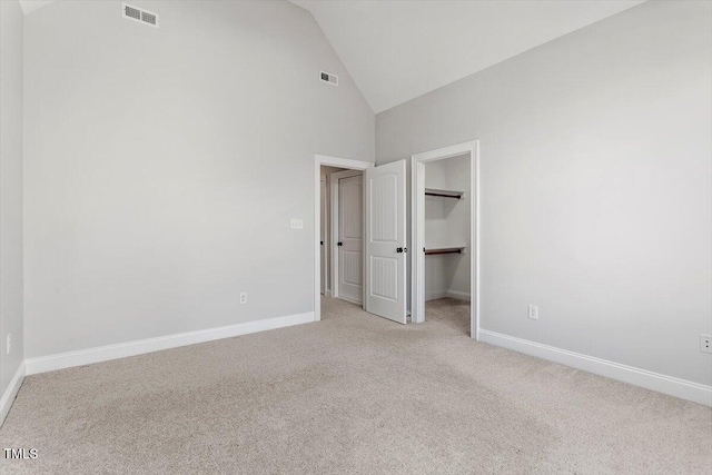 unfurnished bedroom with light carpet, a spacious closet, visible vents, and baseboards